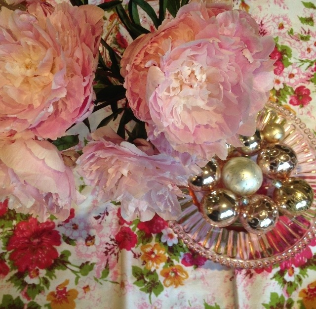 Peonies and baubles in pink cake stand with vintage sheet as tablecloth